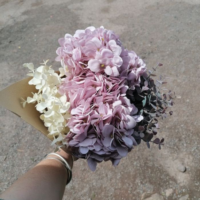 Bouquet of pink and white flowers held by a person on a concrete surface