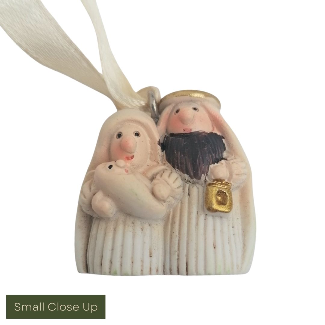 Decorative figurine of a couple with a child, held together by a ribbon, on a white background.