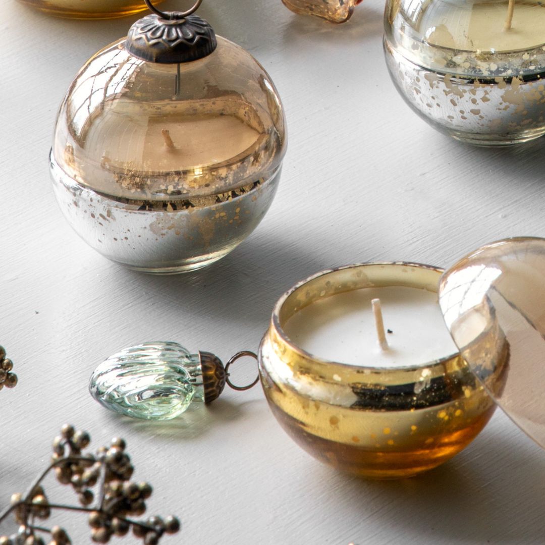 Decorative candles in glass holders on a light surface with small decorative items.