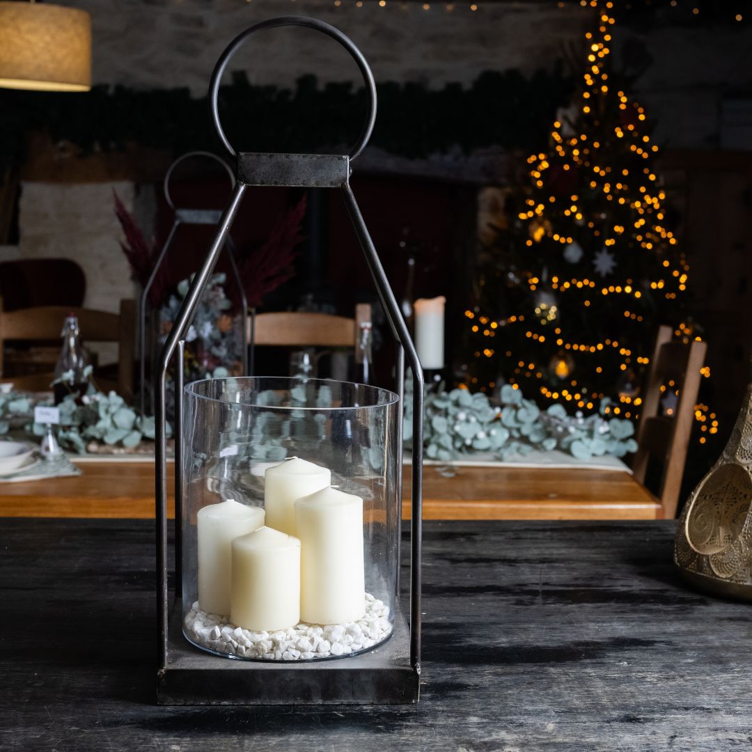Decorative lantern with candles on a table in a festive indoor setting.