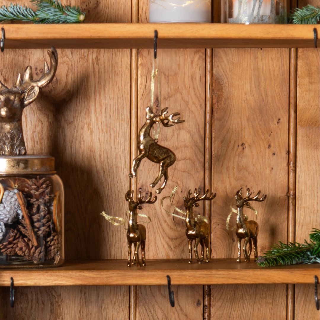Set of gold reindeer decorations on a wooden shelf with a wooden panel background.