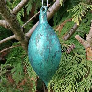 Teal crackle glass Christmas tree decoration against the green of a tree