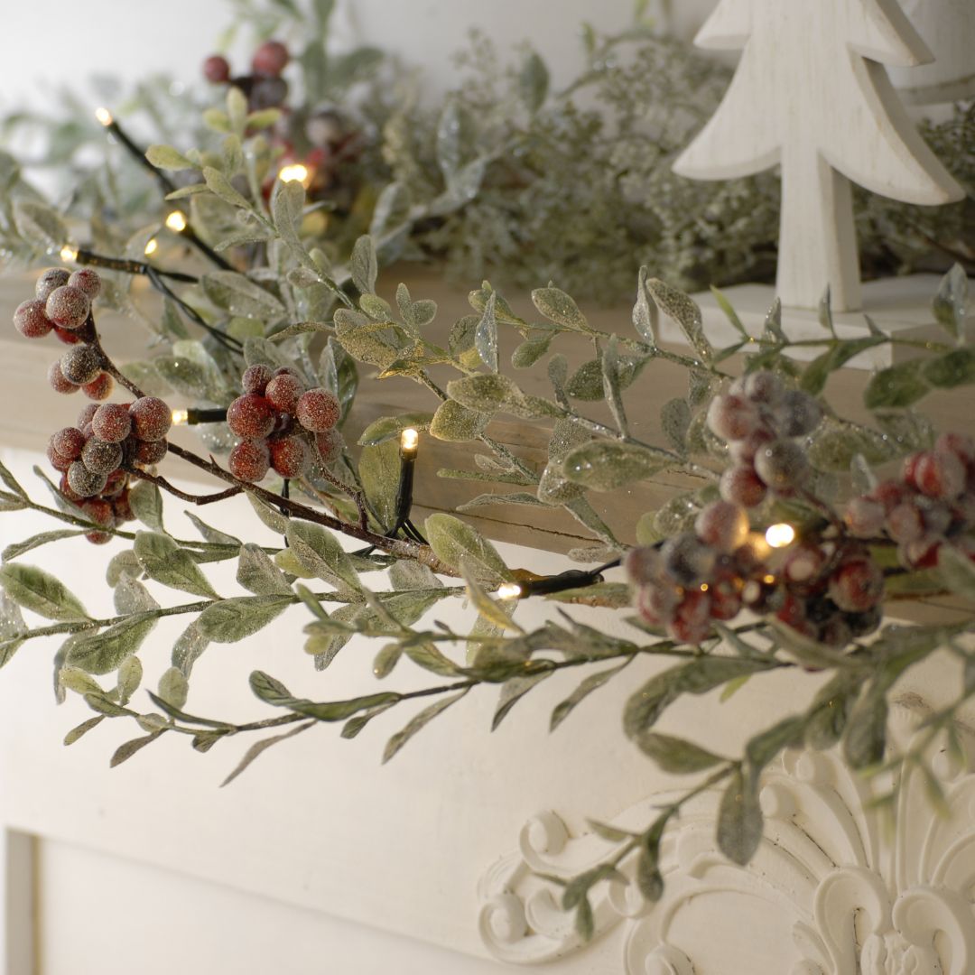 Decorative garland with berries and lights on a white surface