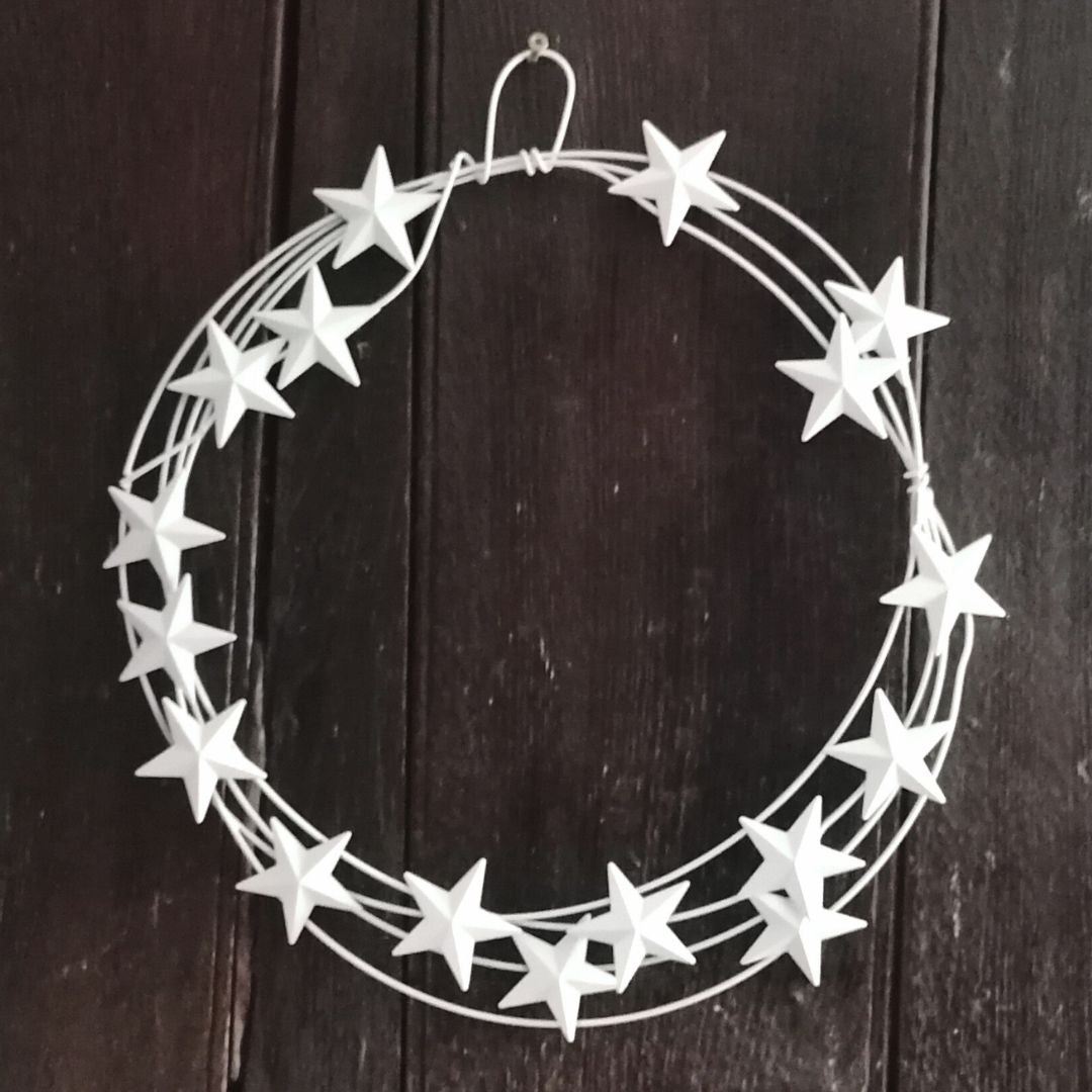 The white star metal wreath hanging on an old, dark wooden door