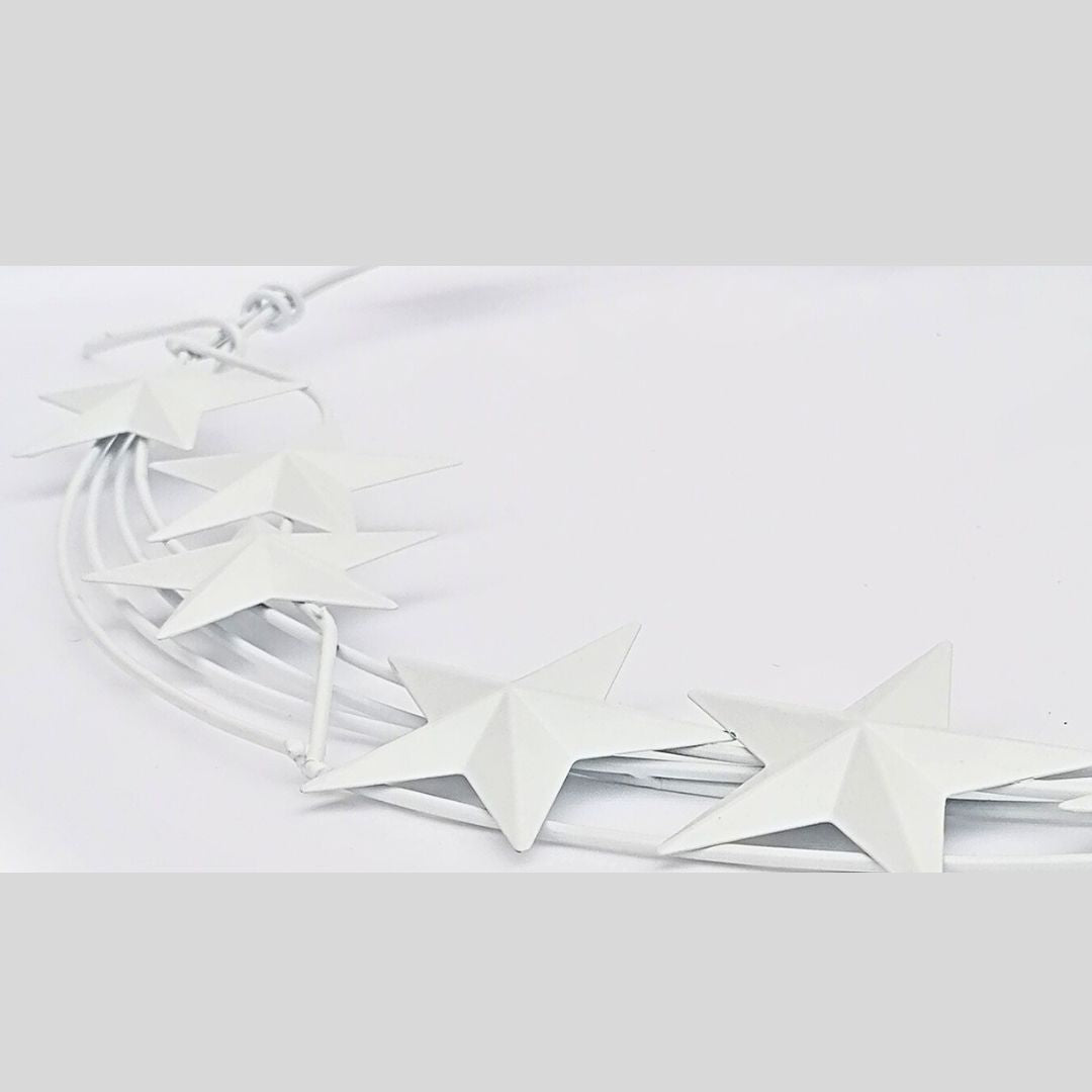 Showing the side view of the white star metal wreath against a white background, bordered with a pale grey