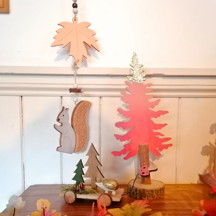 Wooden decorations including a tree, squirrel, and leaf on a white wall background.