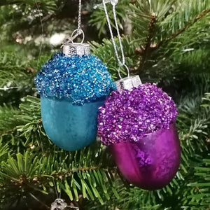 Showing the purple acorn Christmas tree decorations and the turquoise acorn Christmas tree decorations against a fir tree for background