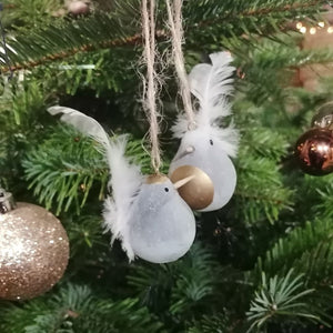 Cement bird Christmas tree decorations showing the gold hat and the gold belly against a green fir background