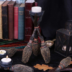 Showing the broomstick tea light candle holder as part of a display with burning tea lights, a lantern and old books