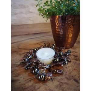 Copper and Brown Berry Foliage Christmas Candle Ring with a tea light candle inside it, and next to a copper beaker with plant inside