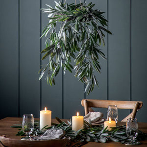 Hanging eucalyptus wreath over a dining table in a dark painted room