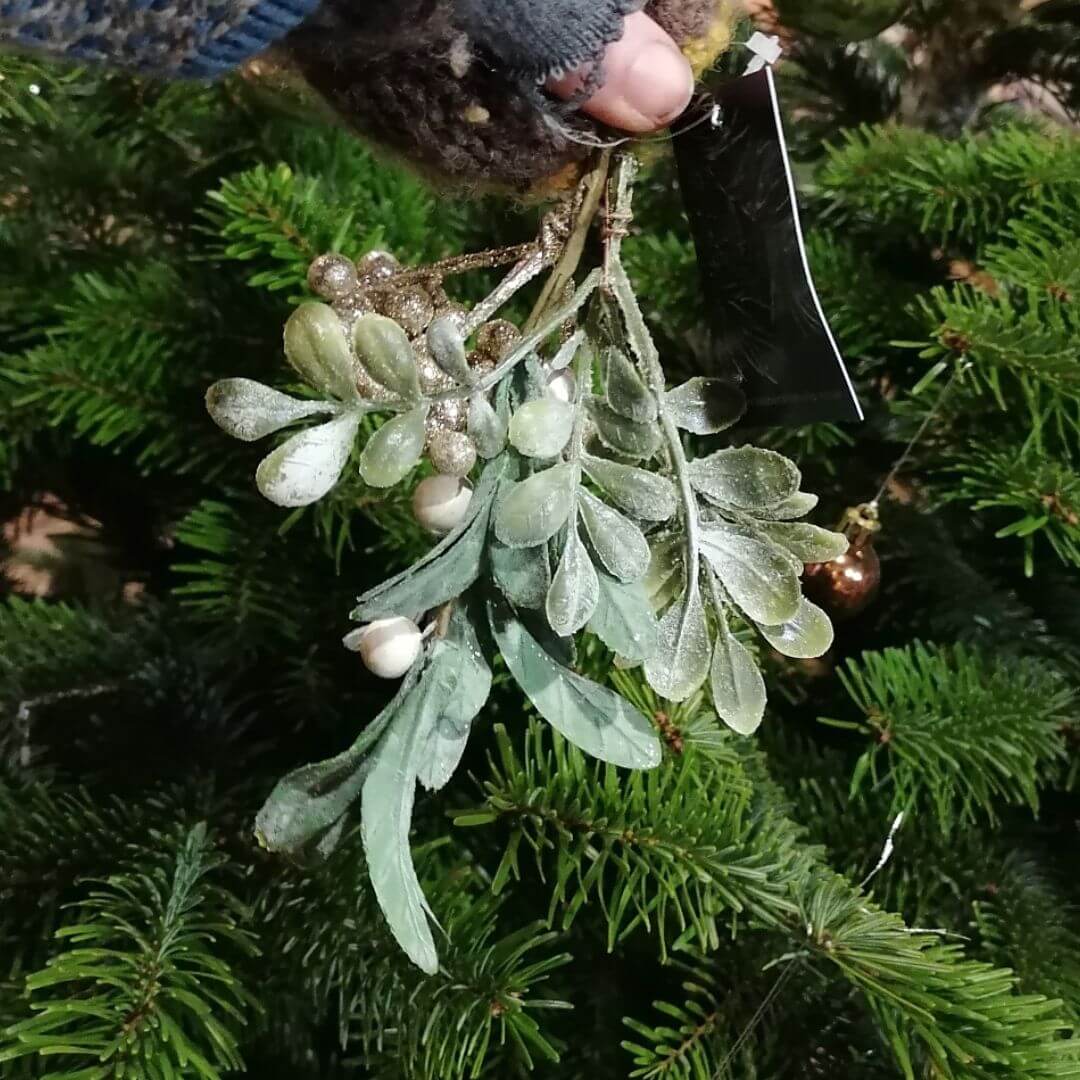 Showing the mistletoe and berries tree decoration against a green Christmas tree background