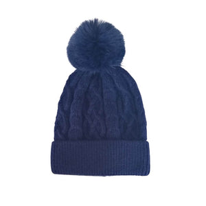 The navy blue knitted hat with faux fur bobble as a flat lay