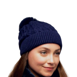 The navy blue knitted hat with faux fur bobble as worn on a model
