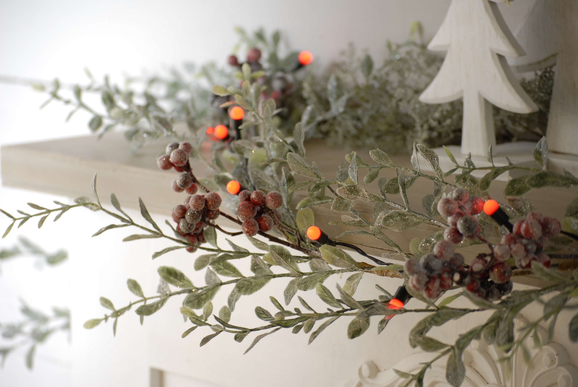 A picture of the red berries Christmas lights on a garland on a mantel