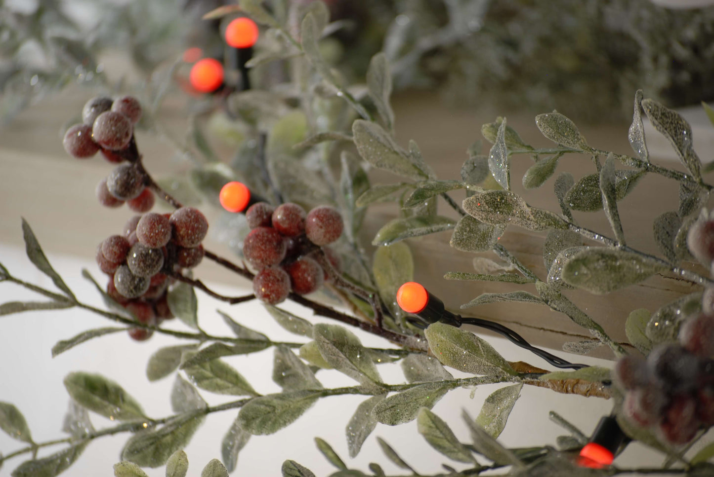 Shwoign a close up of the red berries Christmas lights bulbs next to an artificial berry stem