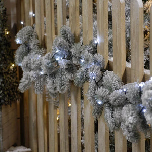 Showing the 1000 cold white LED string Christmas lights on a garland on a fence